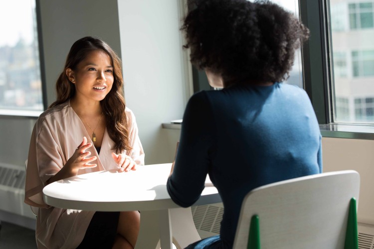 Two students sitting on a chair and having a conversation